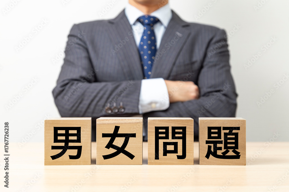 Obraz premium 「男女問題」と書かれたブロックと腕組みをするビジネスマン