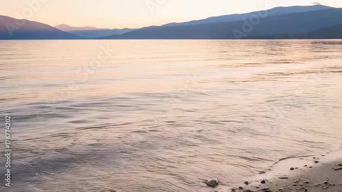 Serene Lake at Dusk with Gentle Waves and Distant Mountains Under a Softly Colored Sky