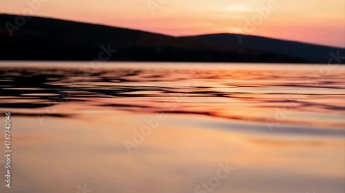 Serene Lake Water Reflecting Golden Sunset Sky Over Silhouetted Hills at Dusk