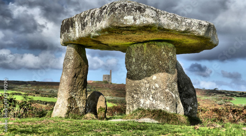 Beautiful and dramatic image of neolithic structure (Lanyon Quoit) in Cornwall with dramatic sky and with engine house of Ding Dong Mine framed by the quoit