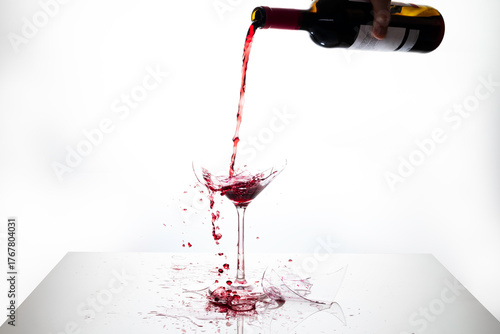 A bottle pours red wine into a broken glass. Splashes. Space available for advertising campaigns. White background.