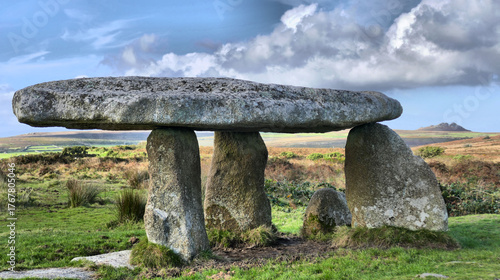 Beautiful and dramatic image of neolithic structure (Lanyon Quoit) in Cornwall with dramatic sky and with the rocky tor, Carn Galva in the background