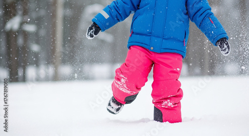 Child in snow pants walking through snowy landscape in winter  