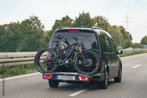 Bike rack mounted on a van driving along a scenic highway on a clear day in early autumn
