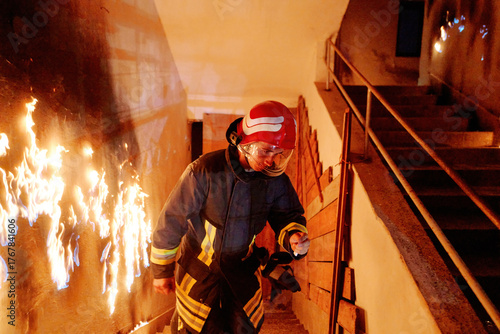 Valokuva Firefighter in action, battling flames in burning building, wearing protective gear and helmet, fire safety and emergency response, danger and rescue, urban environment