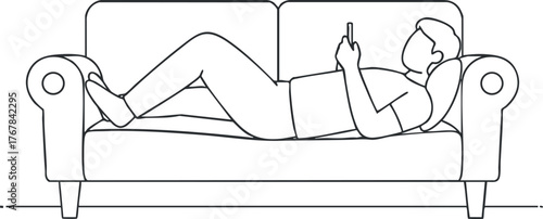 A person lying on a couch using a smartphone, embodying relaxation and leisure at home.