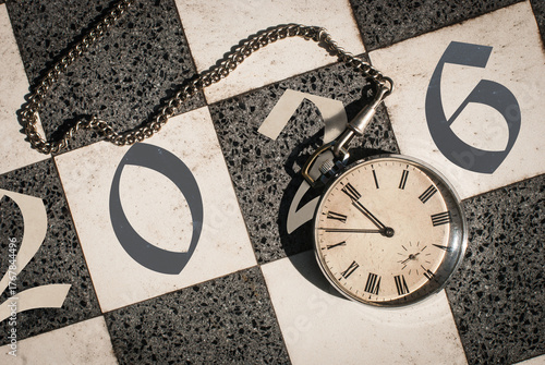 Countdown to 2026 concept. Vintage pocket watch on a chessboard just before midnight.