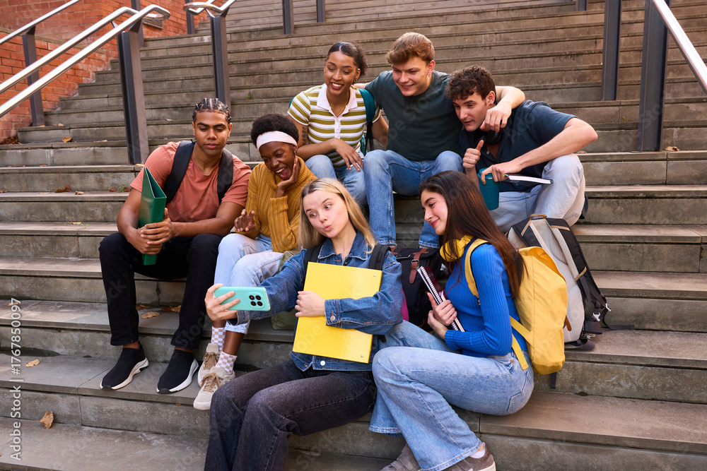 Obraz premium Group of diverse college students taking selfie on campus stairs