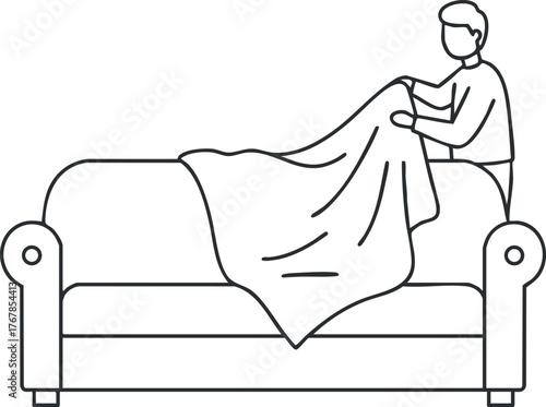 A person arranging a blanket on a sofa in a cozy living room setting.