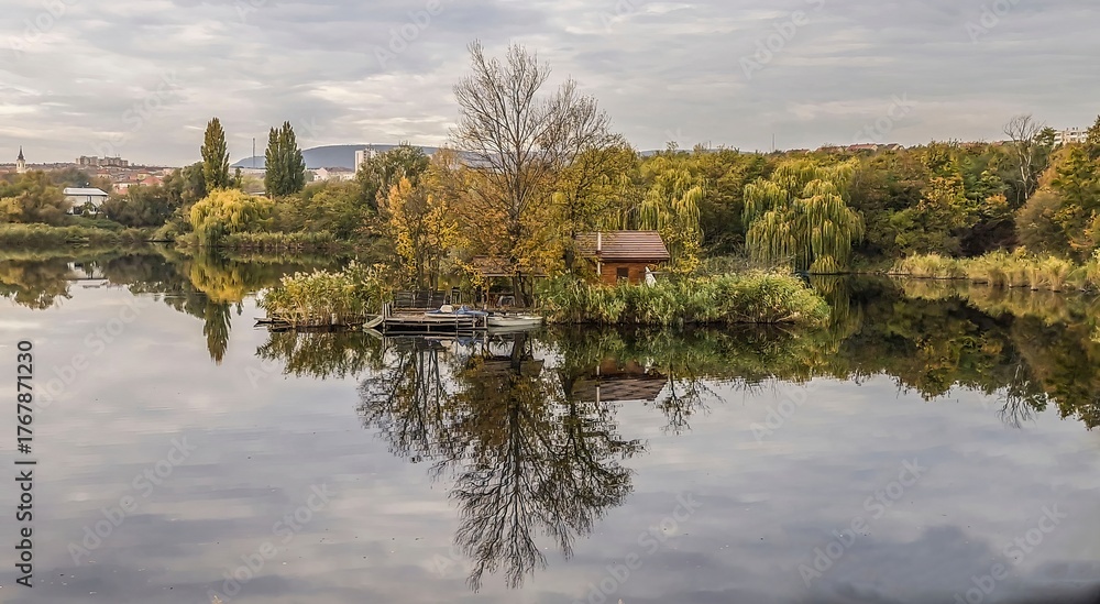 Fototapeta premium Small island with hut reflected in calm lake 