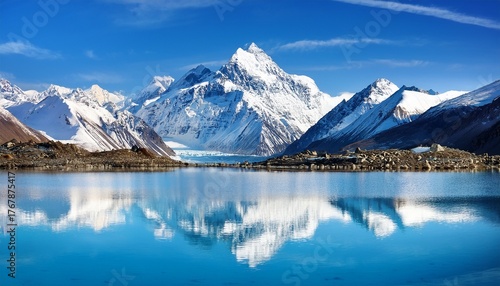 majestic snow capped mountains reflecting in a crystal clear glacial lake under a vibrant blue sky