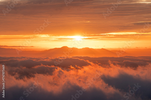山脈の向こうから昇る朝陽と波打つ雲海の絨毯