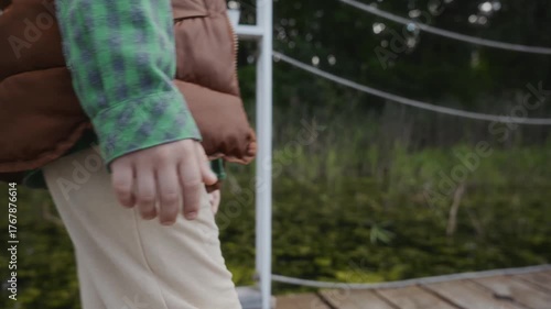 Side view of boy walking alone on wooden pier. Symbolizes growing up, first independence and emotional strength. High quality 4k footage