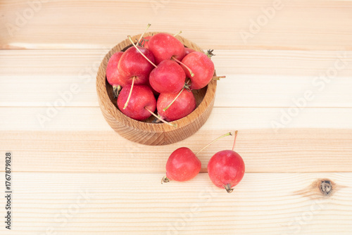 Apples. The fruits of a small-fruited apple tree in a wooden bowl on a light wooden background.