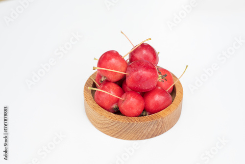 Apples. The fruits of a small-fruited apple tree in a wooden bowl on a white background.