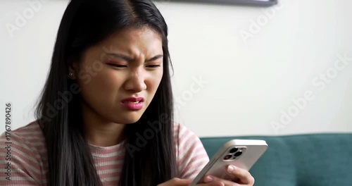 Frustrated woman reacting to smartphone content while sitting indoors