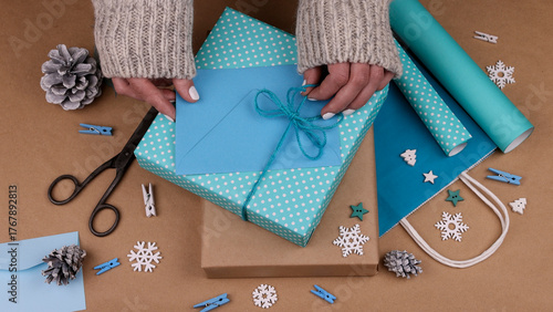 Woman packing Christmas gifts with blue paper