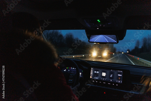 driver navigating rainy city roads, night journey with illuminated dashboard and tense urban