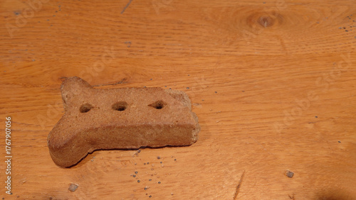 half a broken dog bone biscuit on an oak table top