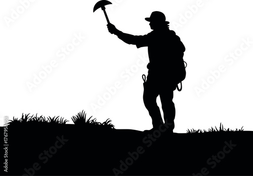 Black silhouette of person with tool on grassy hill