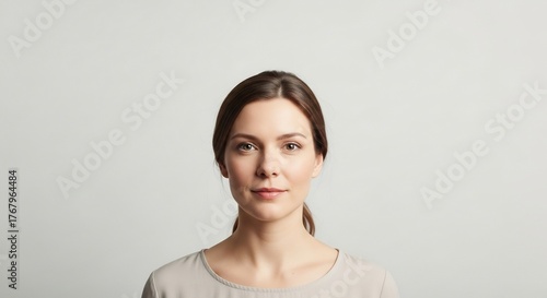 Portrait of a woman with brown hair pulled back wearing a light gray top
