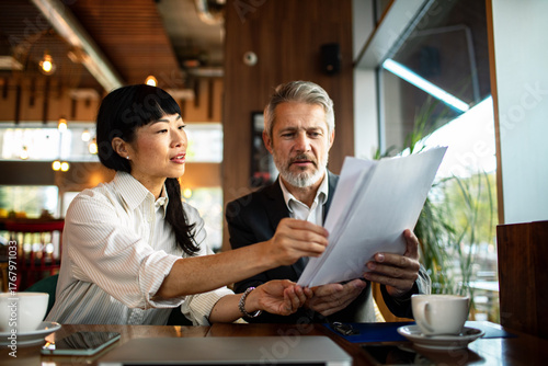 Mature business colleagues reviewing documents in cafe