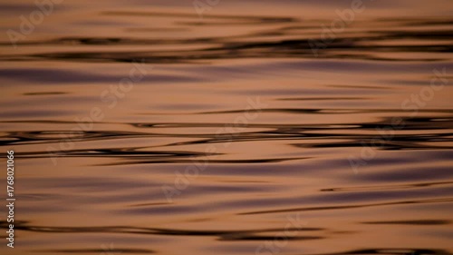 A mesmerizing macro abstract background of a calm water surface with beautiful deep orange and red sunset reflections