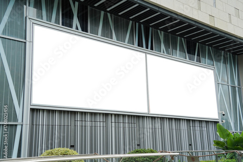 Mockups of two blank white billboards framed by a modern building facade, ideal for advertising
