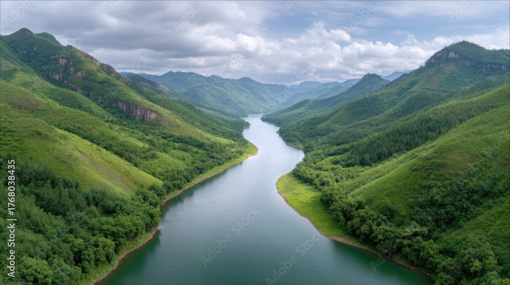 Naklejka premium A Serene River Flows Through Lush Green Mountain Valleys Under a Partly Cloudy Sky in a Tropical Landscape