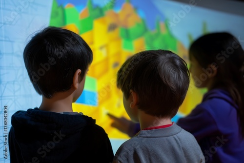 Children stand before a large interactive projection screen to explore educational maps, fostering collaborative learning and discovery in a modern classroom environment.