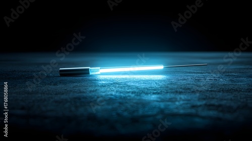 Illuminated narrow implement rests upon a dark, textured surface in low light