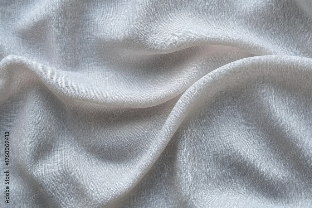 Fototapeta premium Close-up of soft, light gray fabric with gentle folds and textured surface creating smooth flowing patterns
