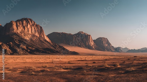 Towering sandstone formations dominate a vast, arid desert landscape during sunset or sunrise