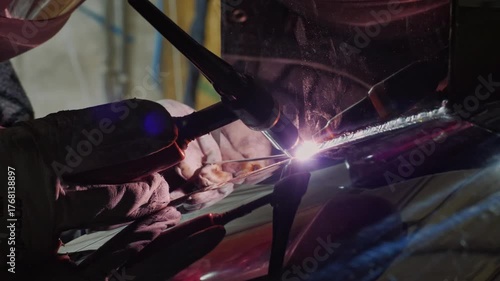 An industrious and technical mood is captured by a close-up of a welder in protective gear using a welding torch, with the bright arc and reflection visible in the shield and surrounding surfaces