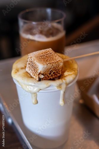 A cup of hot coffee, with Smore, a toasted marshmallow on top