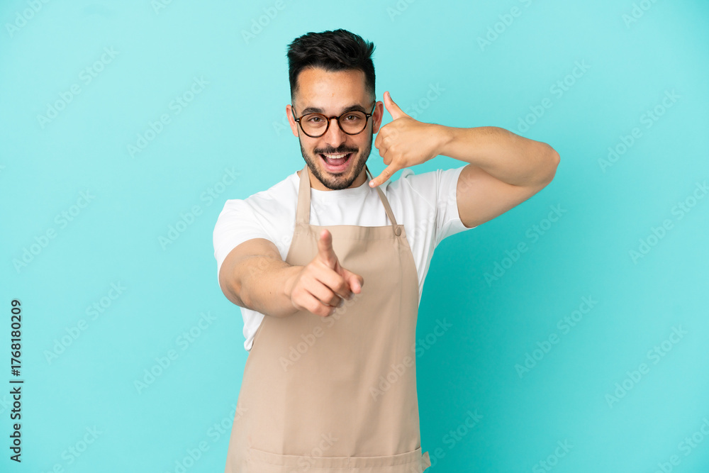 Fototapeta premium Restaurant waiter caucasian man isolated on blue background making phone gesture and pointing front
