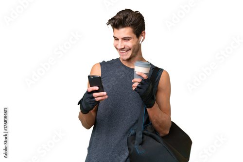 Young sport caucasian man with sport bag over over isolated background holding coffee to take away and a mobile
