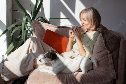 Middle age Woman sitting on sofa and drinking coffee or tea at morning at home