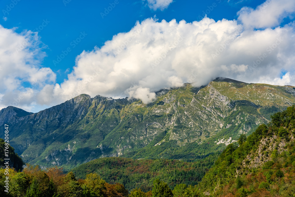 Fototapeta premium Green meadows next to the high mountains of the Julian Alps in the town of Kobarid, Slovenia.