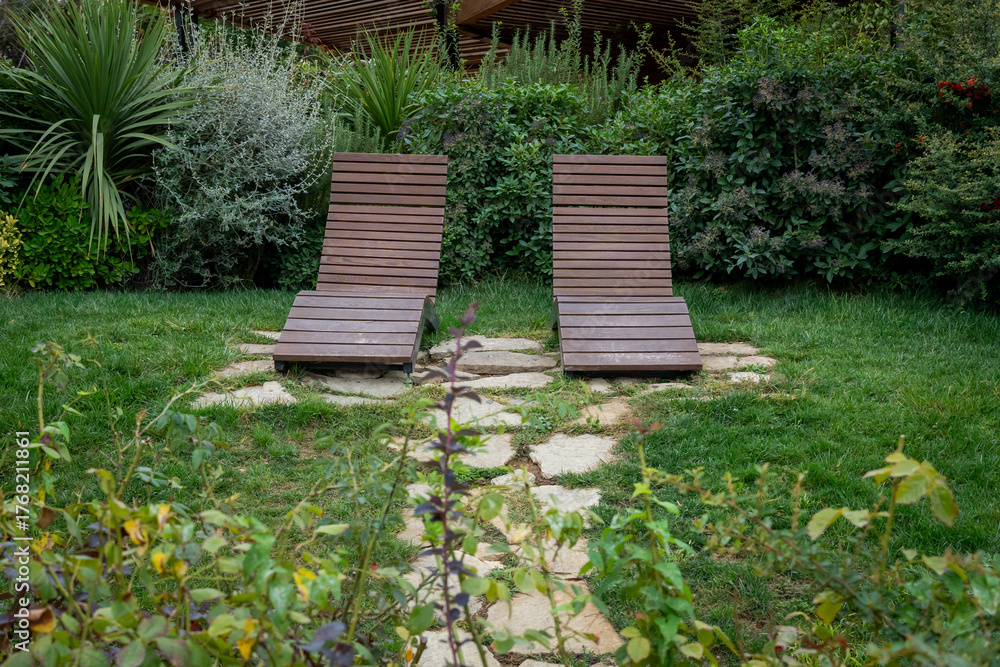 Obraz premium Wooden Lounge Chairs in Lush Garden Setting