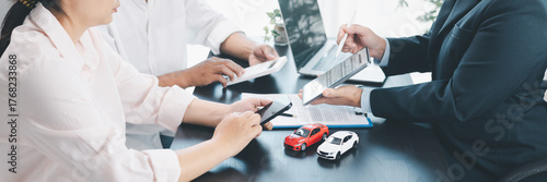 Panorama view of car loan agreement signing with dealer presenting vehicle model, customer using calculator at office desk, concept of auto finance, leasing, insurance and business contract.