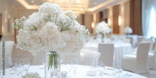 A beautiful arrangement of white flowers in a glass vase, set on an elegantly decorated table in a bright and sophisticated venue.