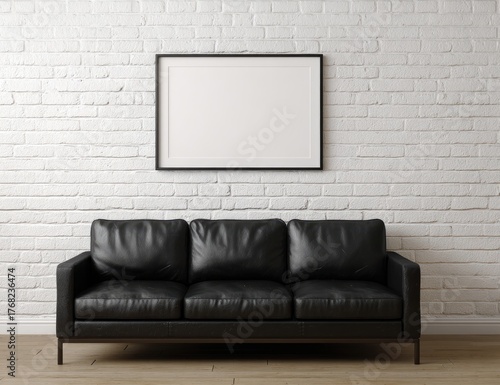 A black leather sofa sits beneath a framed, empty rectangle on a white brick wall