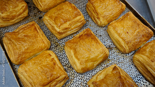 Fresh baked puff pastry squares on baking tray, golden crust close-up