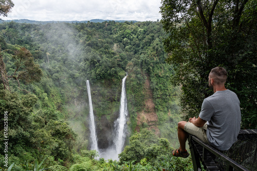 Принти на полотні Man contemplating tad fane waterfall and jungle landscape