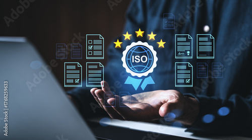 ISO certification concept with quality standart and rating icon surrounded by digital documents over open hands on dark background in business context.