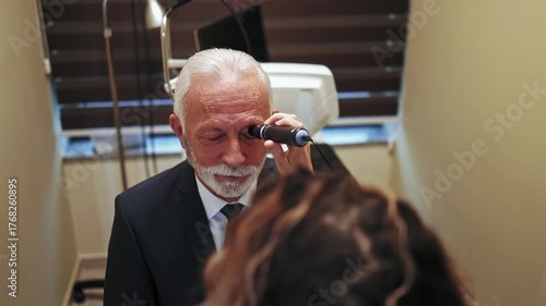 Elderly man in a suit receiving a medical eye check-up from a female optometrist in a modern ophthalmology clinic, using specialized diagnostic equipment for vision and health care