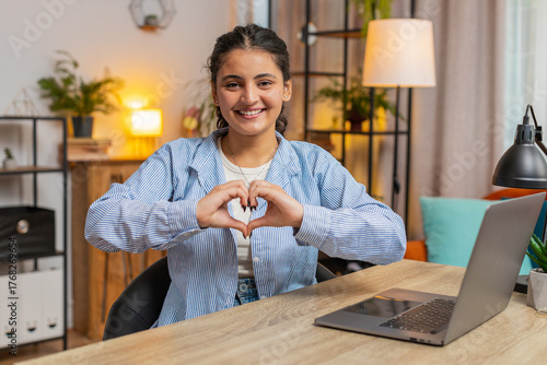 I love you. Indian young woman makes symbol of love, showing heart sign to camera, express romantic feelings, express sincere positive feelings at home office. Charity, gratitude, donation. Lifestyle.