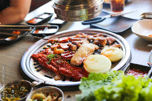 Korea BBQ style restaurant. Asian traditional pickle vegetable ingredients on table with people grilling background.

