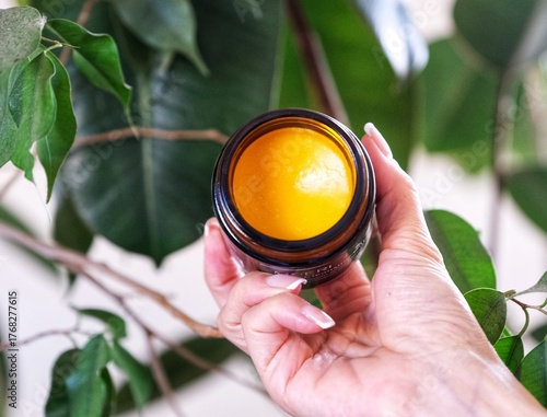 hand holding a jar of orange cleansing balm